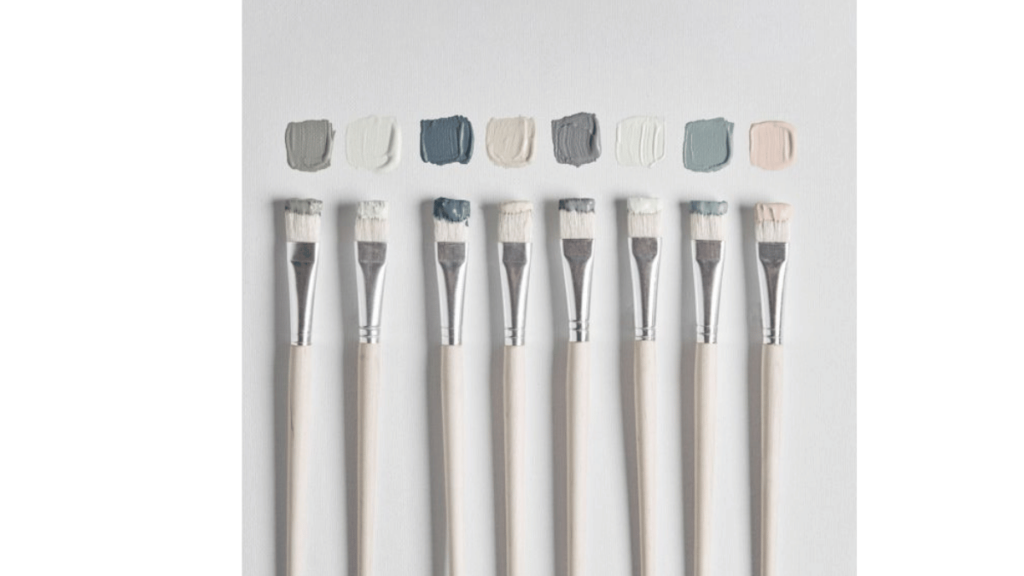 paintbrushes in a row with different coloured paints on the tips
