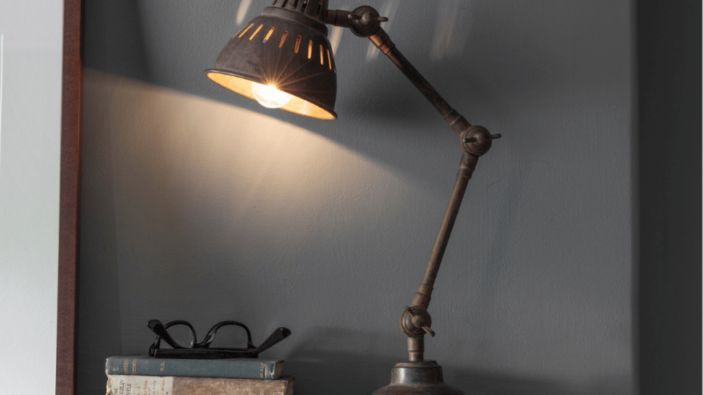 books with a pair of reading glasses next to a study lamp