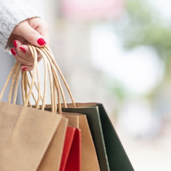 ladies hand holding paper shopping bags