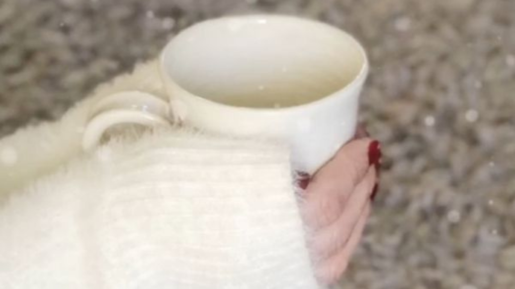 hands engulfed in a fluffy jumper wrapped around a mug
